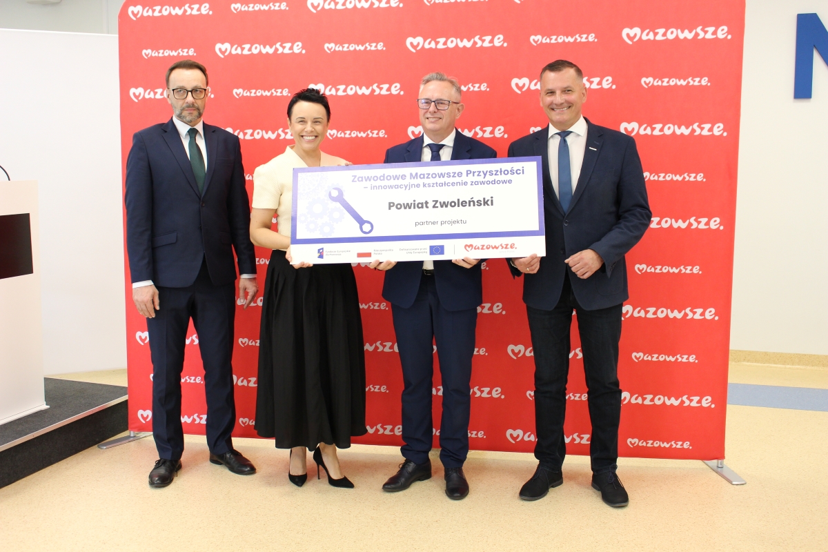 Zdjęcie przedstawia kobietę i trzech mężczyzn stojących na ściance 